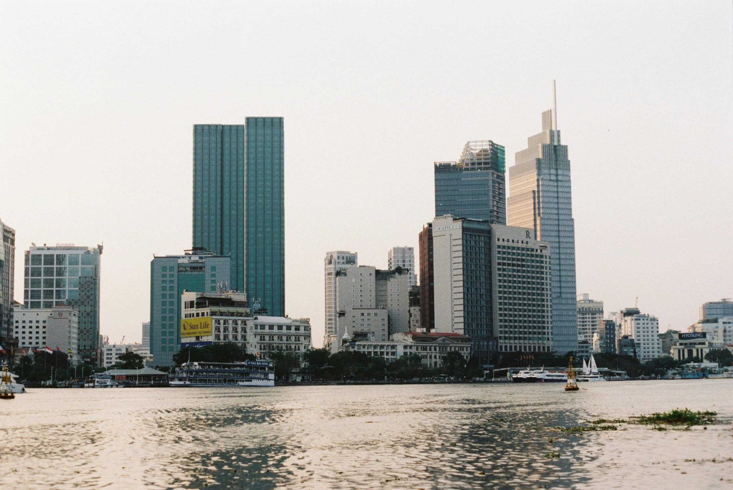 A modern city skyline with skyscrapers along the riverfront during daytime.