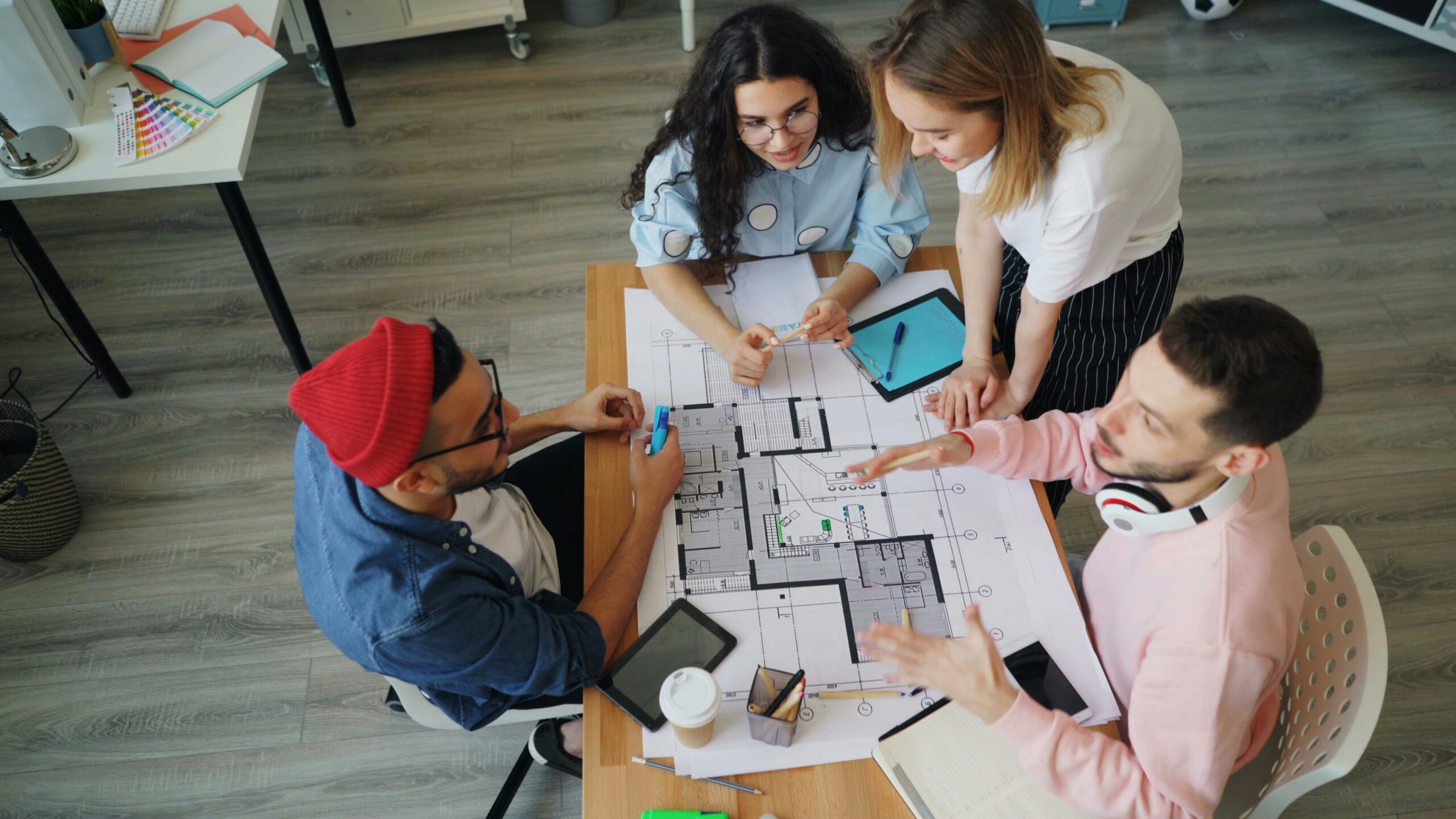Group of diverse adults discussing architectural plans in a modern office setting.